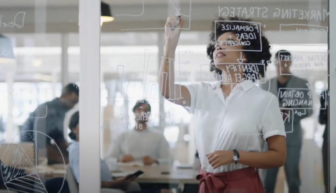 Woman drawing strategy on window whiteboard